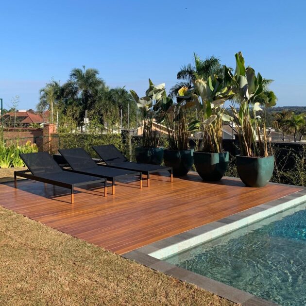 Deck de madeira com espreguiçadeiras à beira da piscina