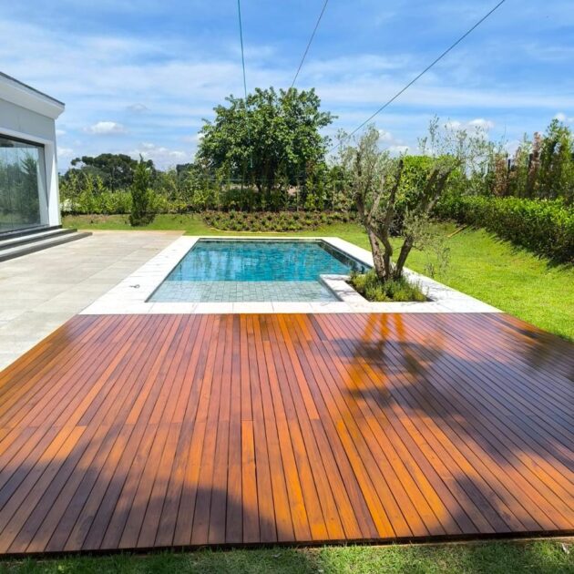 Deck de madeira ao lado da piscina com jardim